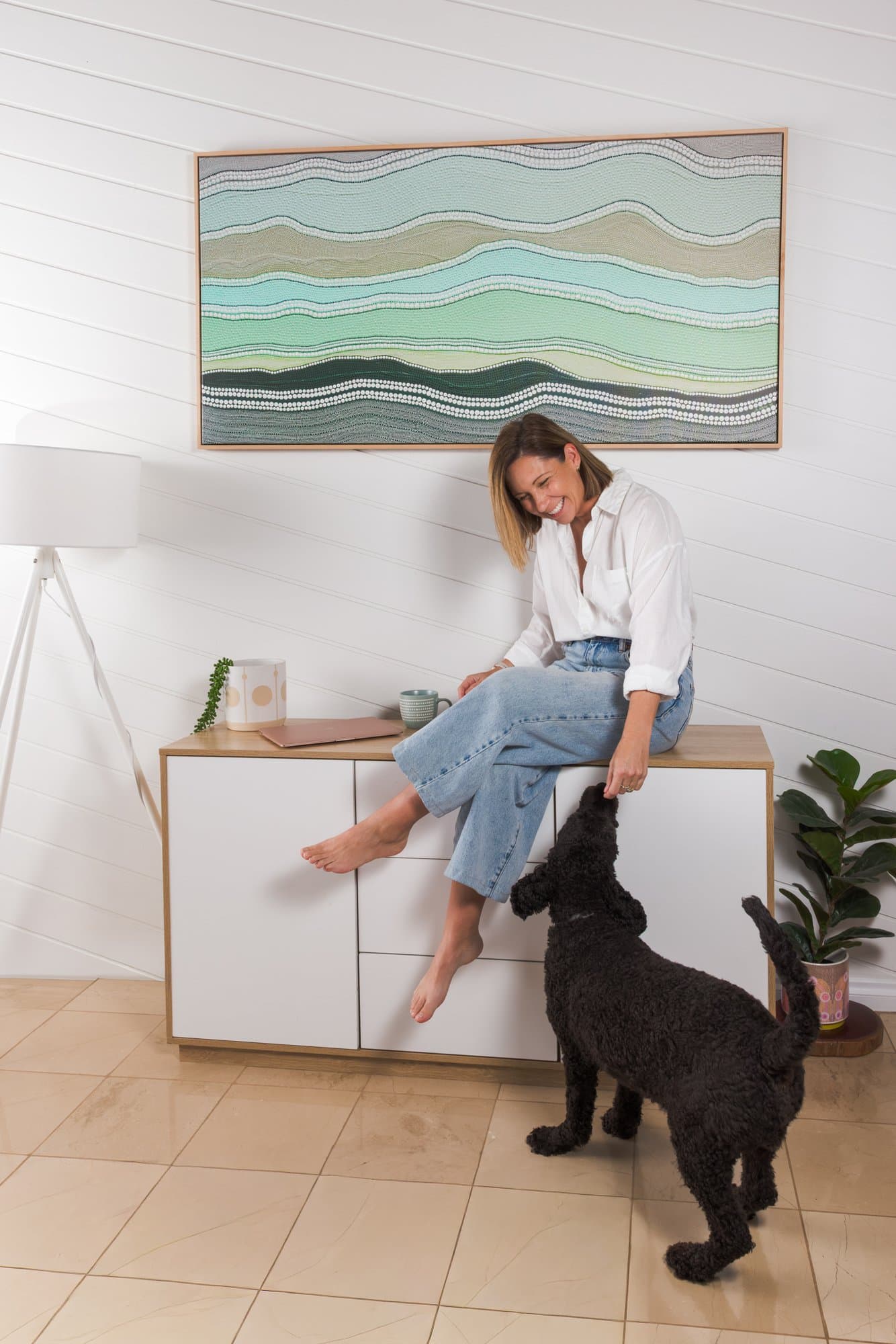 Steph sitting on a sideboard laughing with her dog
